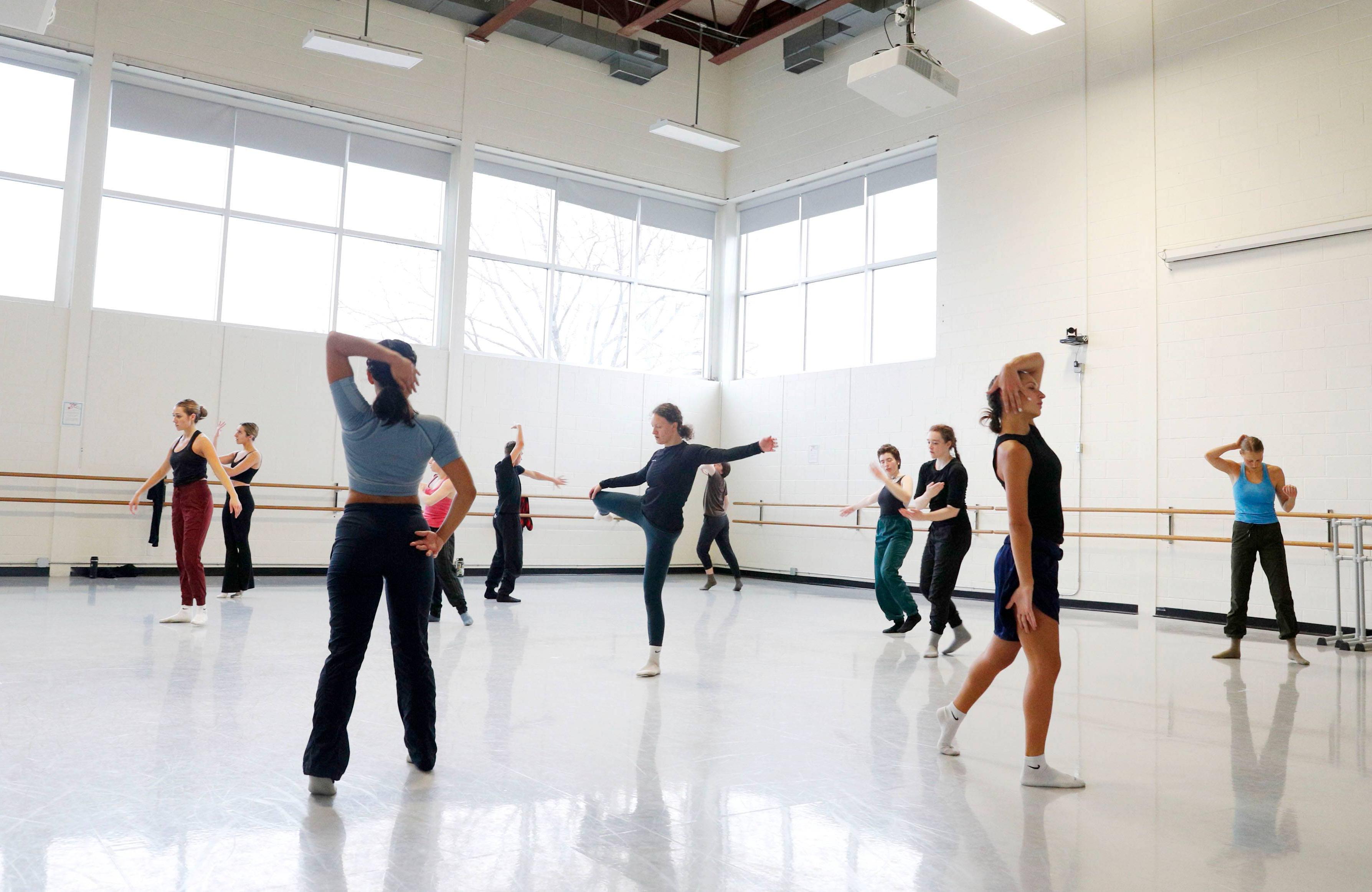 A dozen dancers practice in a white dance student